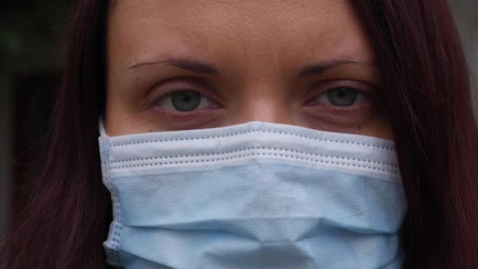 一个有着蓝眼睛和医用口罩的女人的特写脸。