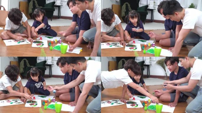父亲看着一群小孩坐在地板上，用水彩画在纸上画了一幅有趣的画。大哥和两个兄弟姐妹，兄弟和最小的妹妹在周