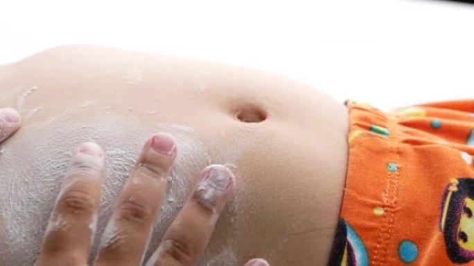 姐姐在床上的姐姐肚子上涂抹婴儿爽身粉的特写。