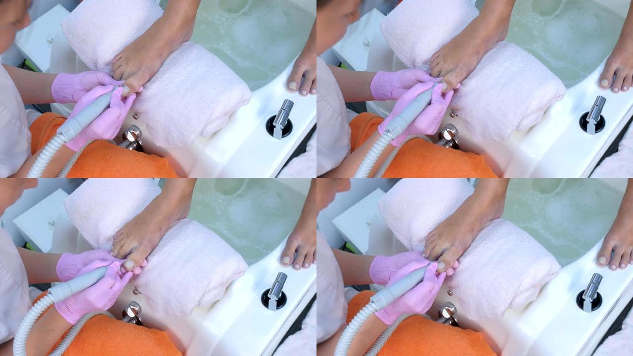 修脚的女人用电动钉甲机从客户的脚趾上去除角质层。