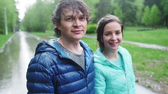 下雨天站在公园里的年轻夫妇的肖像