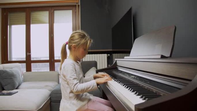 小女孩在家弹钢琴。孩子在客厅弹钢琴。孩子在家学习钢琴。音乐课，中景侧视图。