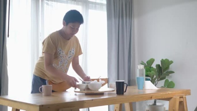 亚洲青春期男孩在家吃完早餐后清理所有食物和菜肴，生活方式理念良好的家政理念。