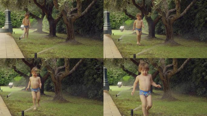 小男孩玩得开心。蹒跚学步的男孩在花园里洒水玩乐的坦率时刻