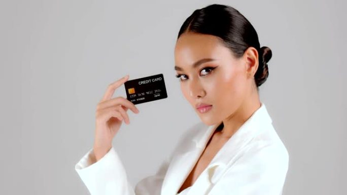 美丽的亚洲女商人出示信用卡并看着相机