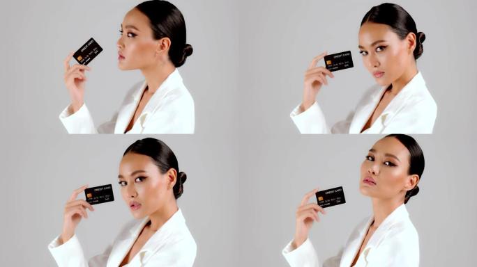 美丽的亚洲女商人出示信用卡并看着相机
