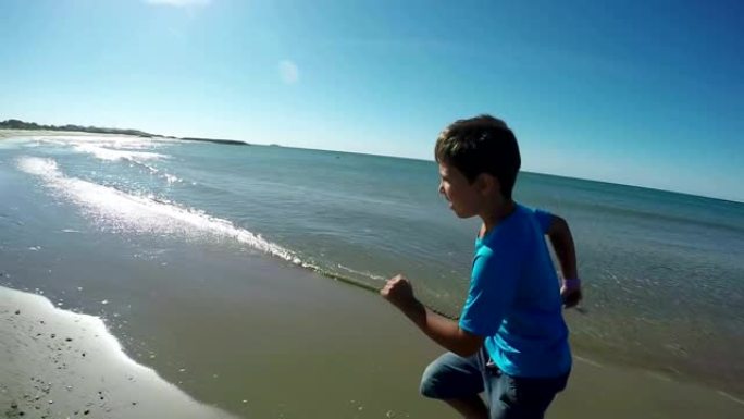 这个开朗的男孩在大海的背景下沿着海岸线奔跑