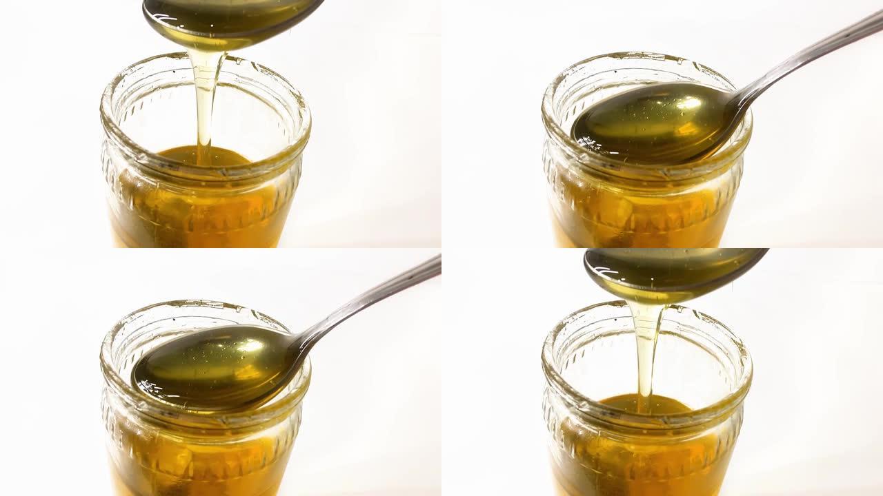 循环视频。金糖浆从勺子滴入玻璃容器。甜蜂蜜