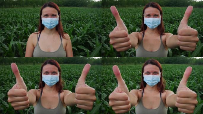 一个戴着医用口罩站在玉米田里的女人双手竖起大拇指。