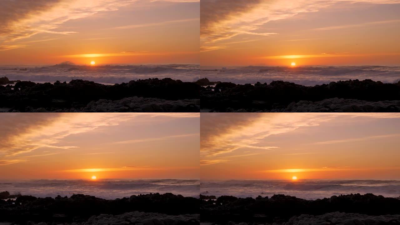 慢动作太平洋大浪在暴风雨天气下在加利福尼亚州蒙特利半岛的太平洋格罗夫的日落天空下滚滚并在多岩石的海岸
