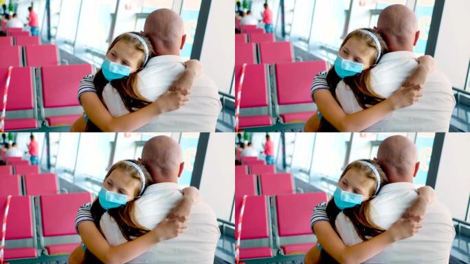 肖像，戴着防护面具的女童在机场候机室空座位的背景下拥抱她的父亲。冠状病毒疫情后航班开通