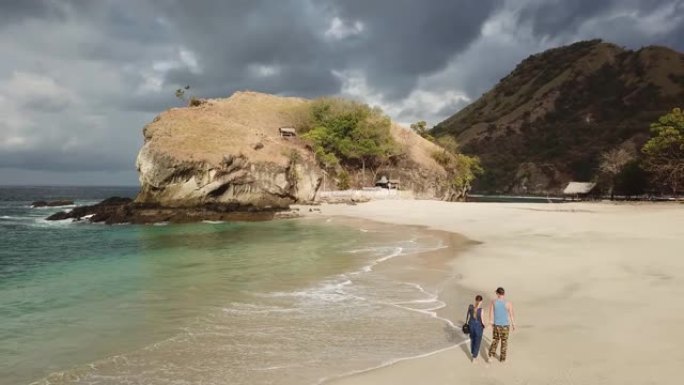 夫妇牵着手走在田园诗般的科卡海滩上。印度尼西亚弗洛雷斯的隐藏宝石。夫妇正在享受他们浪漫的逃亡。波浪轻