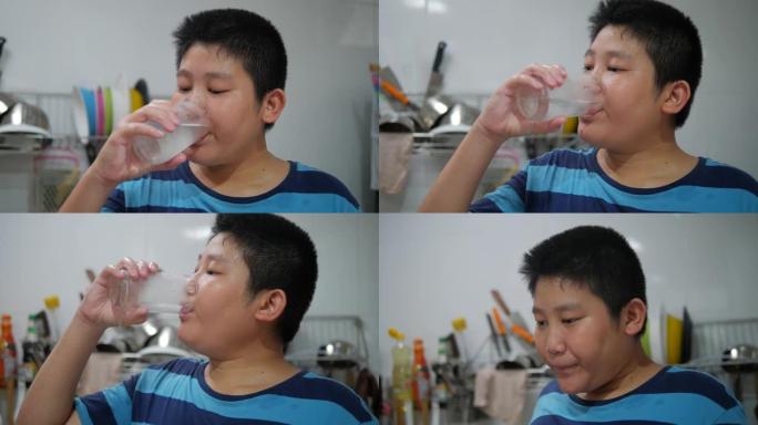 快乐的亚洲青春期男孩在家厨房喝一杯冷水，生活方式理念。