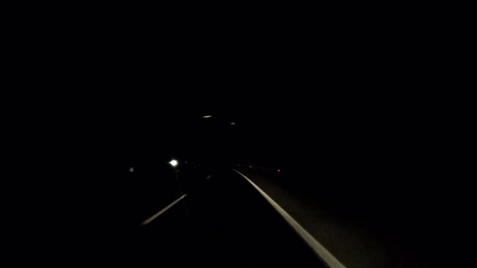 在黑暗的夜晚，在空旷的道路上行驶。一辆汽车在高速公路上行驶。新路白线沥青