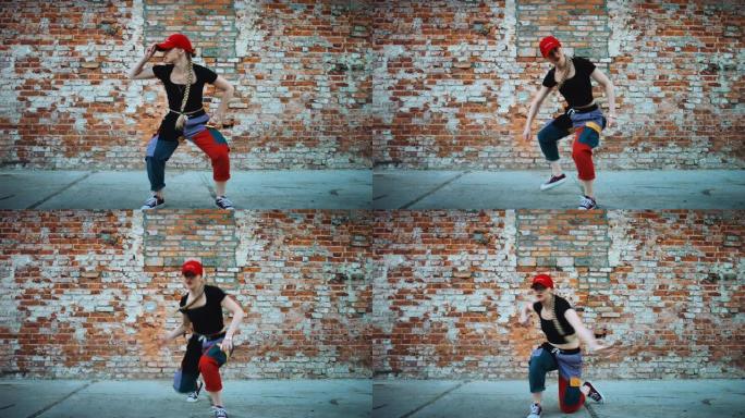 开朗的年轻女子戴着帽子，在城市砖墙旁边的街道上积极跳舞。穿着五颜六色的裤子。127bpm股票视频
