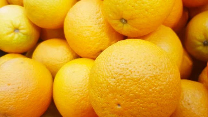 新鲜成熟的橙子，黄橙背景淘给买家。4K.新鲜水果在商店里提供美味的全景果汁。