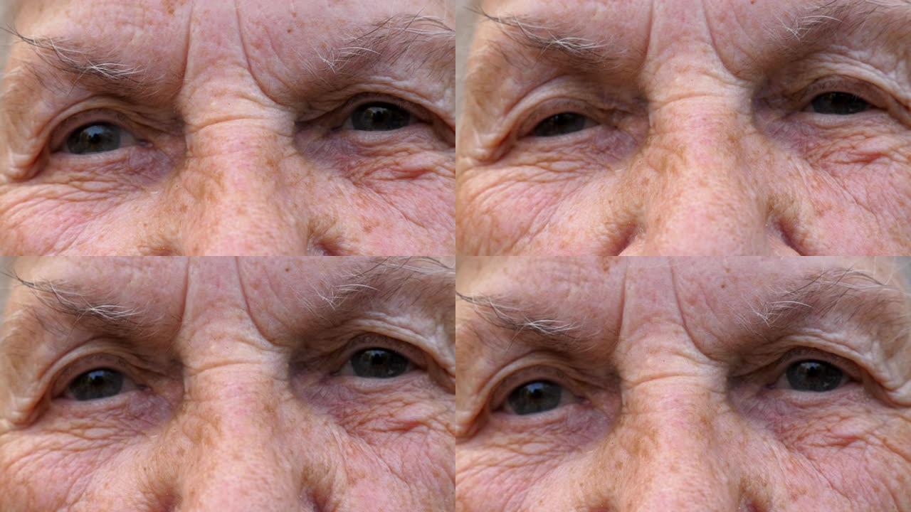 年迈的祖母的肖像带着悲伤的景象看着镜头。关闭成熟女人的灰色眼睛，周围有皱纹。高年级奶奶悲伤的面部表情