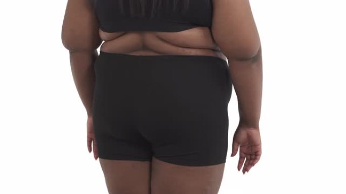 无法辨认的黑人肥胖妇女穿着内衣的背部摇晃她的身体孤立在白色背景上