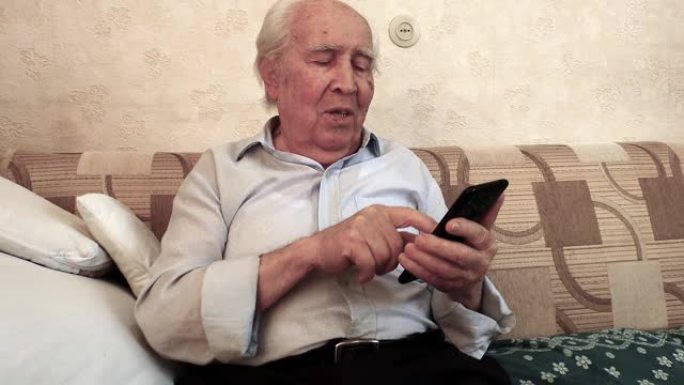 一位老人坐在房间里，面带微笑，拿着智能手机学习