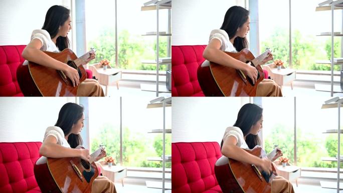 亚洲女人弹吉他，独自唱一首歌。新的正常生活方式和社交距离。在客厅放松和娱乐。