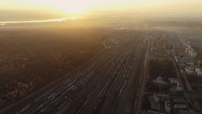 一架无人机在火车站上空起飞。空中俯视图。日落时的铁路分拣站。货站的许多货车。调车场大型交通枢纽全景。
