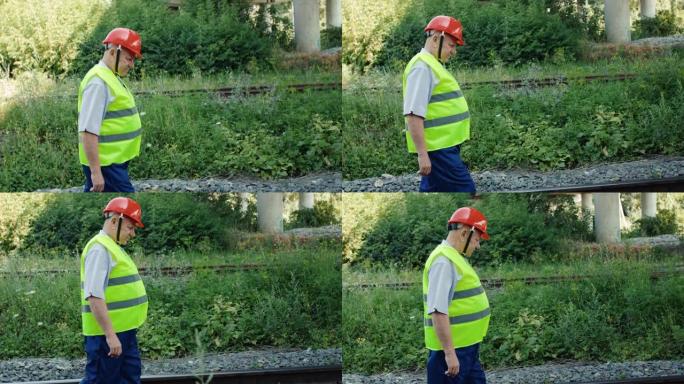 穿着制服的高级铁路工人在铁路上行走以检查适用性