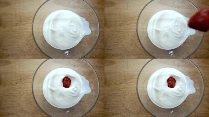 草莓在带有酸奶油的碗里慢动作落下