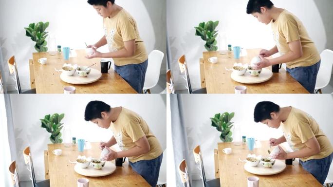 亚洲青春期男孩在家吃完早餐后清理所有食物和菜肴，生活方式理念良好的家政理念。