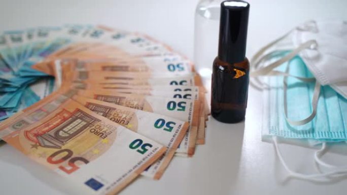 欧元纸币储蓄用于医疗保健和医疗，欧元纸币躺在白色背景附近的医疗防护口罩和小玻璃瓶中的液体补救。药品，