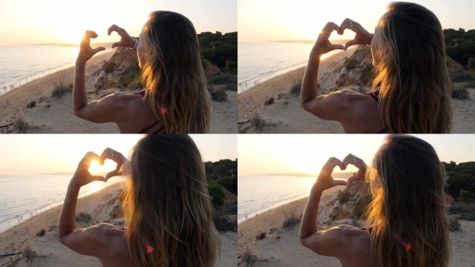 女人在日出时热爱自然，用手制作心形指框