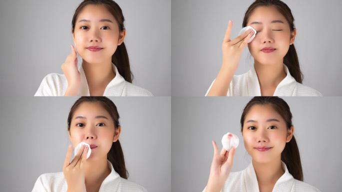 美丽的年轻亚洲妇女拿着洗面奶瓶，用化妆棉涂抹乳液或清洁剂到她的美容脸上去除化妆品。漂亮女孩对笑脸感到