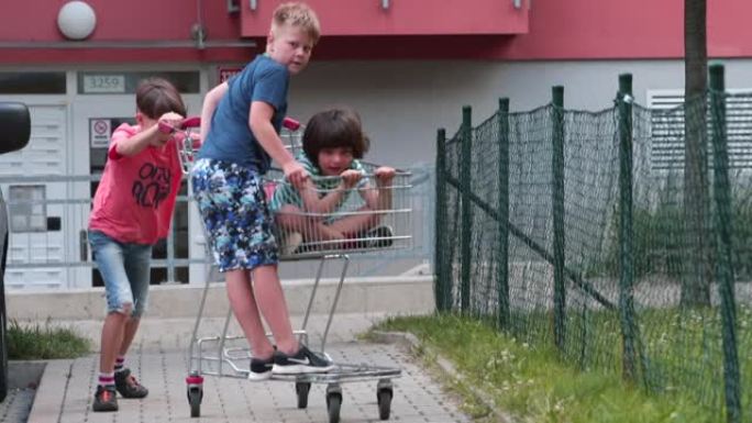 暑假，有趣的孩子在城里玩杂货店的购物车。