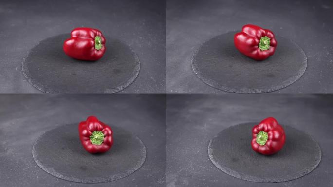 红色甜椒在黑色圆形石头背景上旋转。五彩蔬菜收获的概念