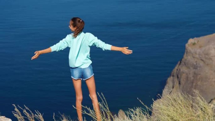 在山顶上举起双手的女旅行者