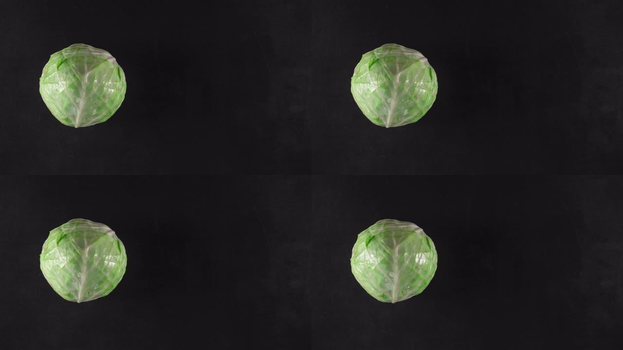在黑色背景上使用绿色卷心菜停止运动动画，俯视图，复制空间。素食的概念或带有蔬菜的广告