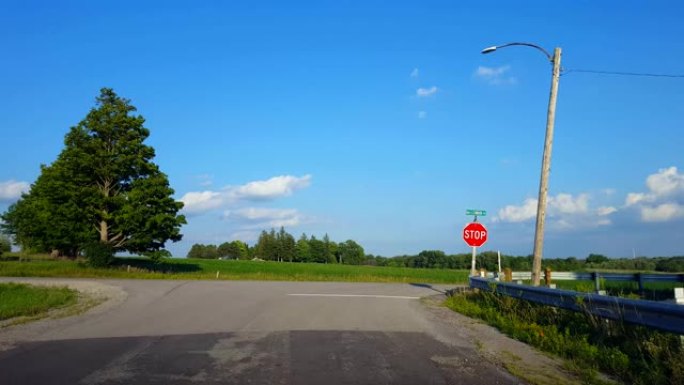 开车绕过道路弯道，接近乡村停车标志，停车，然后右转。驾驶员视点POV驾驶员接近路标并转弯。