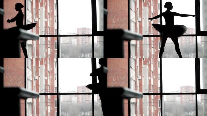 剪影。芭蕾舞女演员在窗户和城市的背景下，穿着黑色芭蕾舞短裙跳舞。慢动作。静态框架。