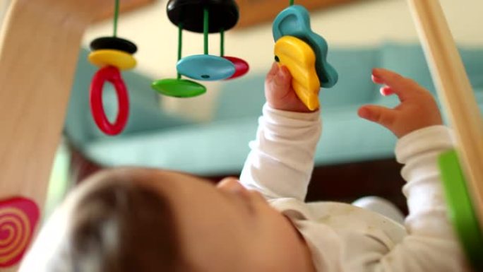 婴儿手握玩具，近距离婴儿玩耍，儿童发育躺在地板上
