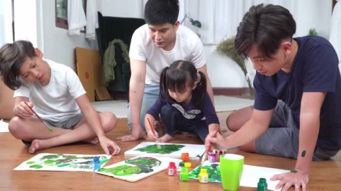 父亲看着一群小孩坐在地板上，用水彩颜料在纸上学习和娱乐绘画。周末，老大哥和两个兄弟姐妹在客厅里一起休
