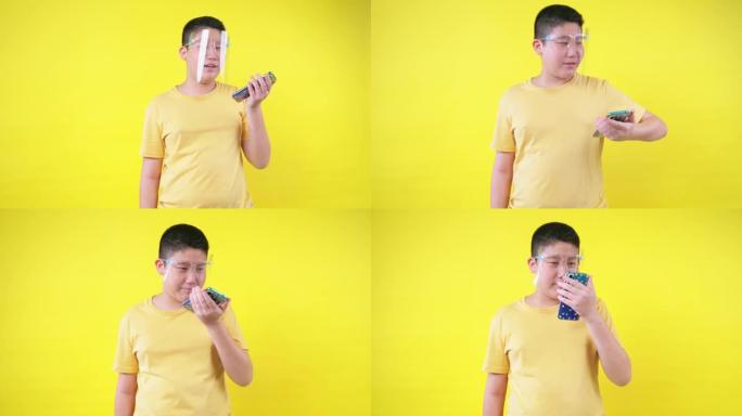 快乐的亚洲青春期男孩戴着口罩，玩黄色背景的网络游戏，新的正常概念。