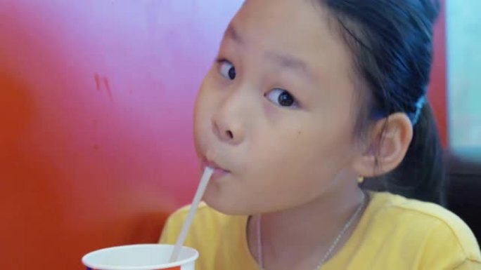 亚洲女孩在咖啡馆用塑料吸管喝一些饮料。