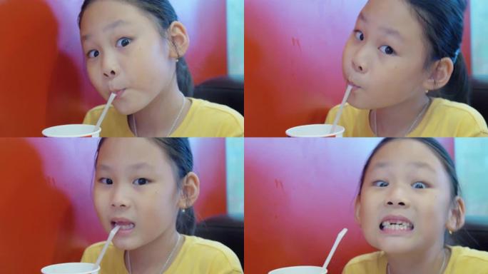 亚洲女孩在咖啡馆用塑料吸管喝一些饮料。