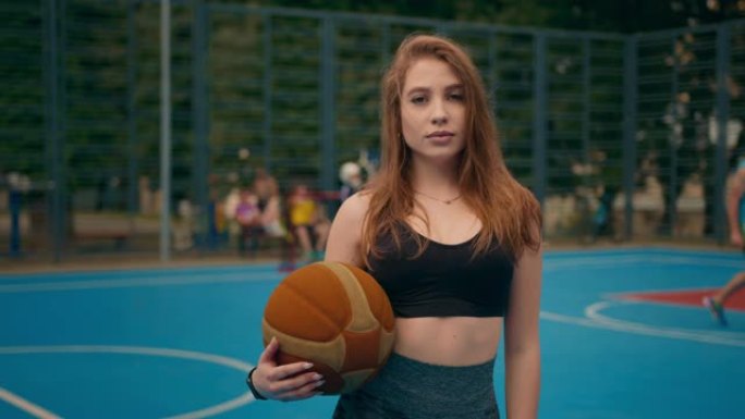 近距离射击。一个运动女孩的肖像。那个女孩正看着照相机。她拿着一个篮球。照相机在圆周运动。4 k \