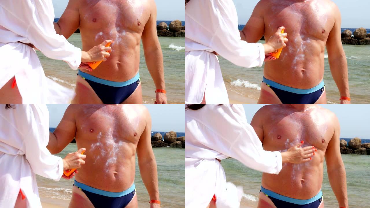 特写，在男人皮肤上涂抹防晒霜或喷雾乳液。在海滩上，在烈日下，在大海的背景下。防晒和防紫外线。皮肤保护