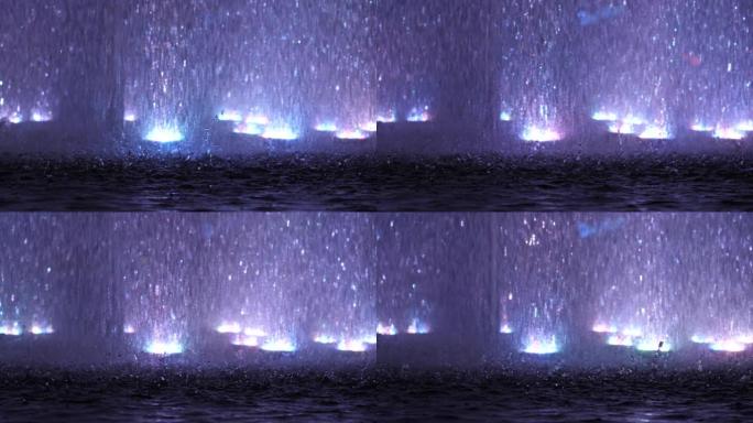 粉红的光芒在喷泉中发光，照亮了下落的水滴-慢动作模式