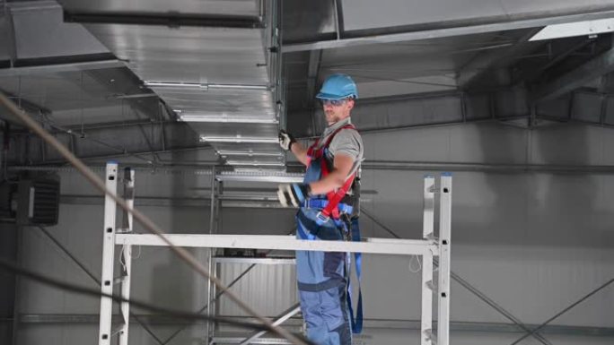 新建筑工地天花板上新安装的通风口的男性承包商收紧部分的关闭。