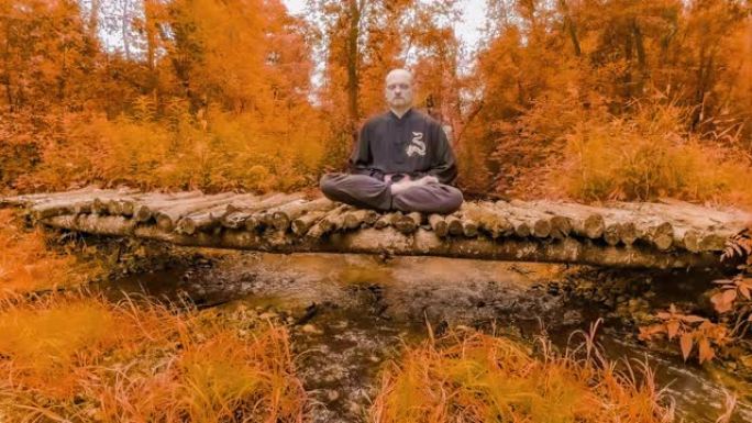 延时。一个人在小溪上的木桥上冥想。在红叶周围。