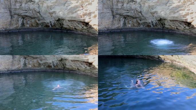 年轻女子在山洞旁的自然泳池中跳跃和游泳