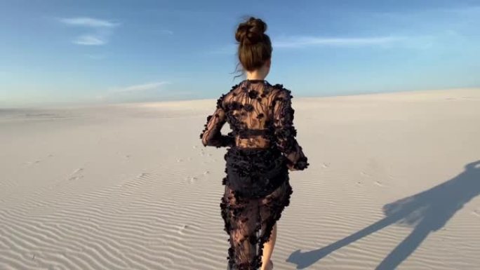 穿着蕾丝黑色连衣裙的女人在沙漠中奔跑。