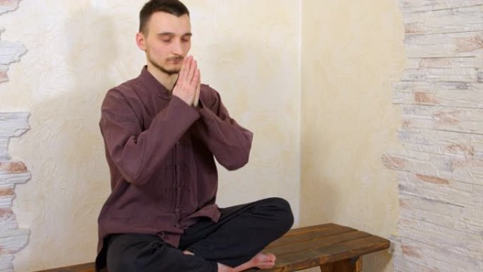 荷花放松的人在木凳上与脉轮冥想。瑜伽男子在木墙背景上的莲花体式练习脉轮冥想。